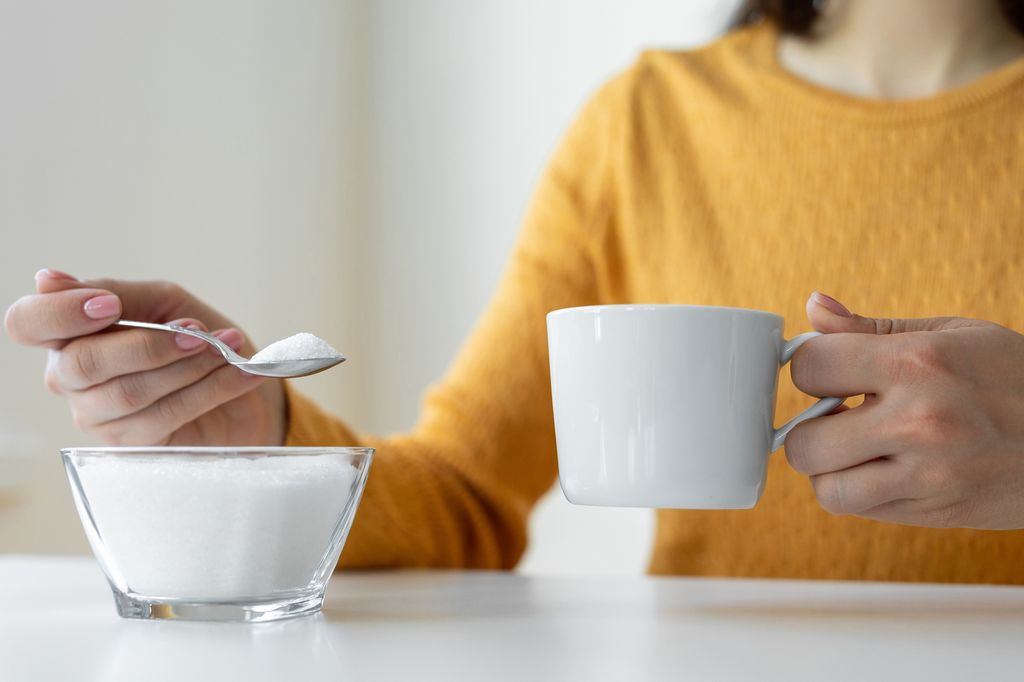 Woman adding sugar to hot drink