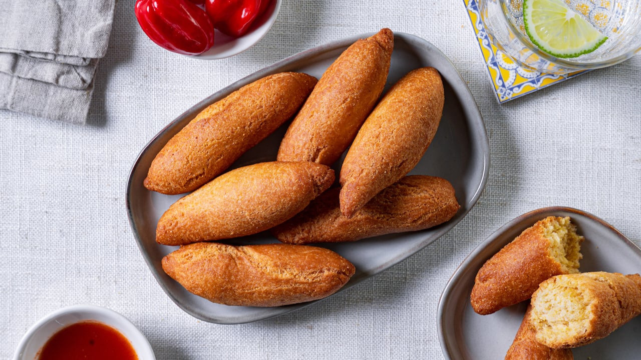 Top down shot of a platter of festival (golden-brown dumplings) on a grey tablecloth.