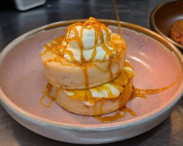 Drizzling golden syrup on a stack of crumpets.