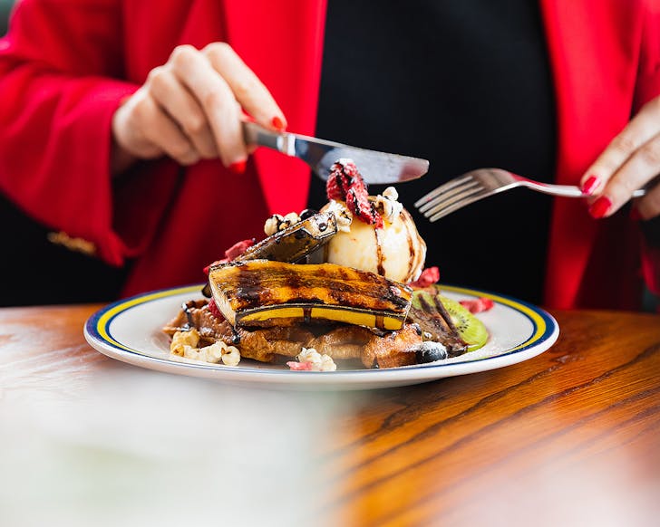 Someone tucks into a pancake stack at The Breakfast Club, one of the best breakfasts in Auckland.