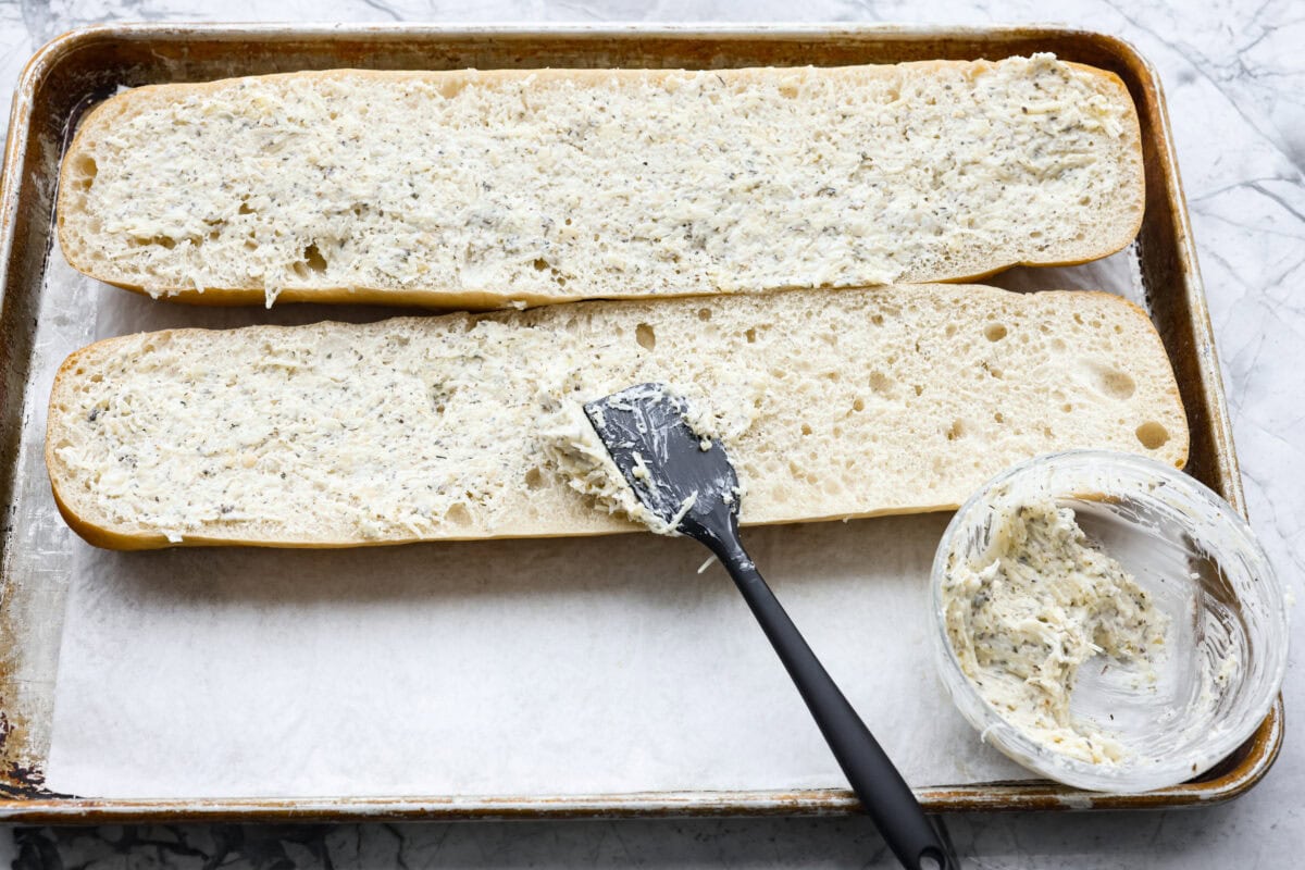 I’m not saying I’ve eaten half a loaf of this Garlic Bread straight off the baking sheet…but I’m also not not saying that. It’s golden, cheesy, dripping with garlicky butter, and so good! Someone spreading garlic butter on the French bread.
