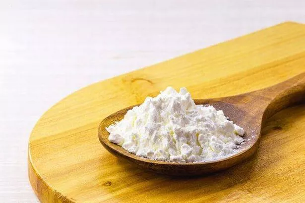 spoon with cornstarch, flour made from corn used to make creams or as a thickener. White background, copy space