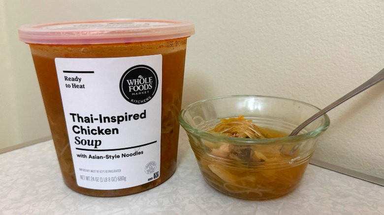 A tub and small glass bowl filled with Thai-Inspired Chicken Soup