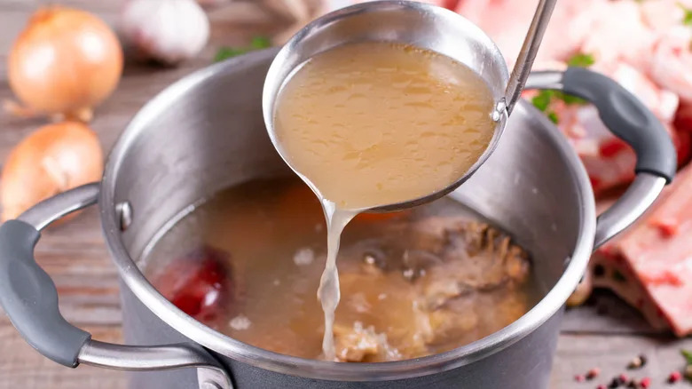 Ladel of stock being poured into a stock pot.