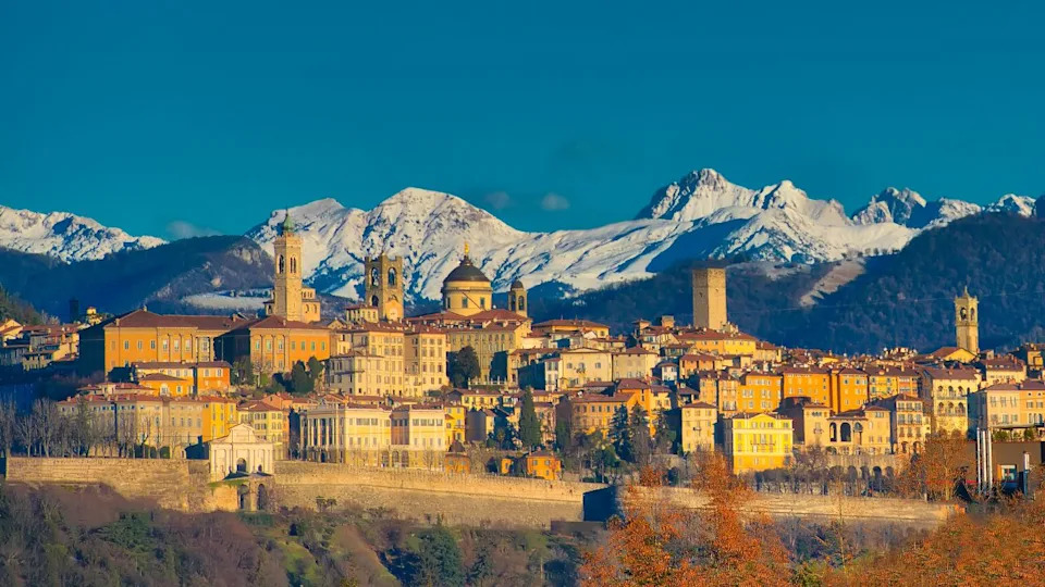The city of Bergamo with high behind the White Mountains of snow the early morning sun