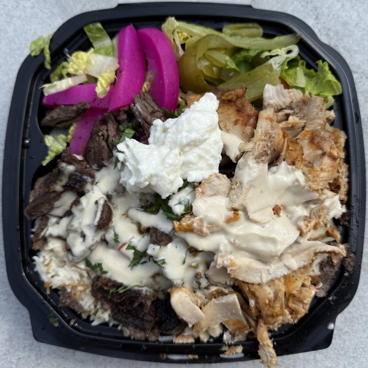 Mixed shawarma platter from Souk Al Shater in Sunnyside, Queens. Crispy shaved pieces of tender meat that go perfectly with the creamy and garlicky toum, tahini sauce, and salad with pickles.