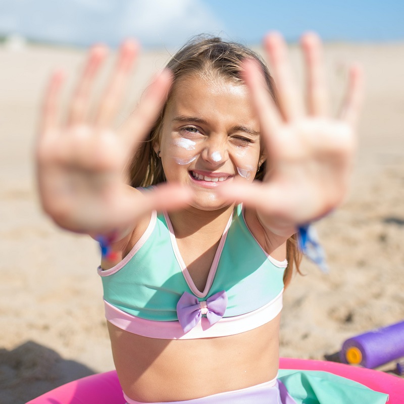 A young girl with sunblock on her face.