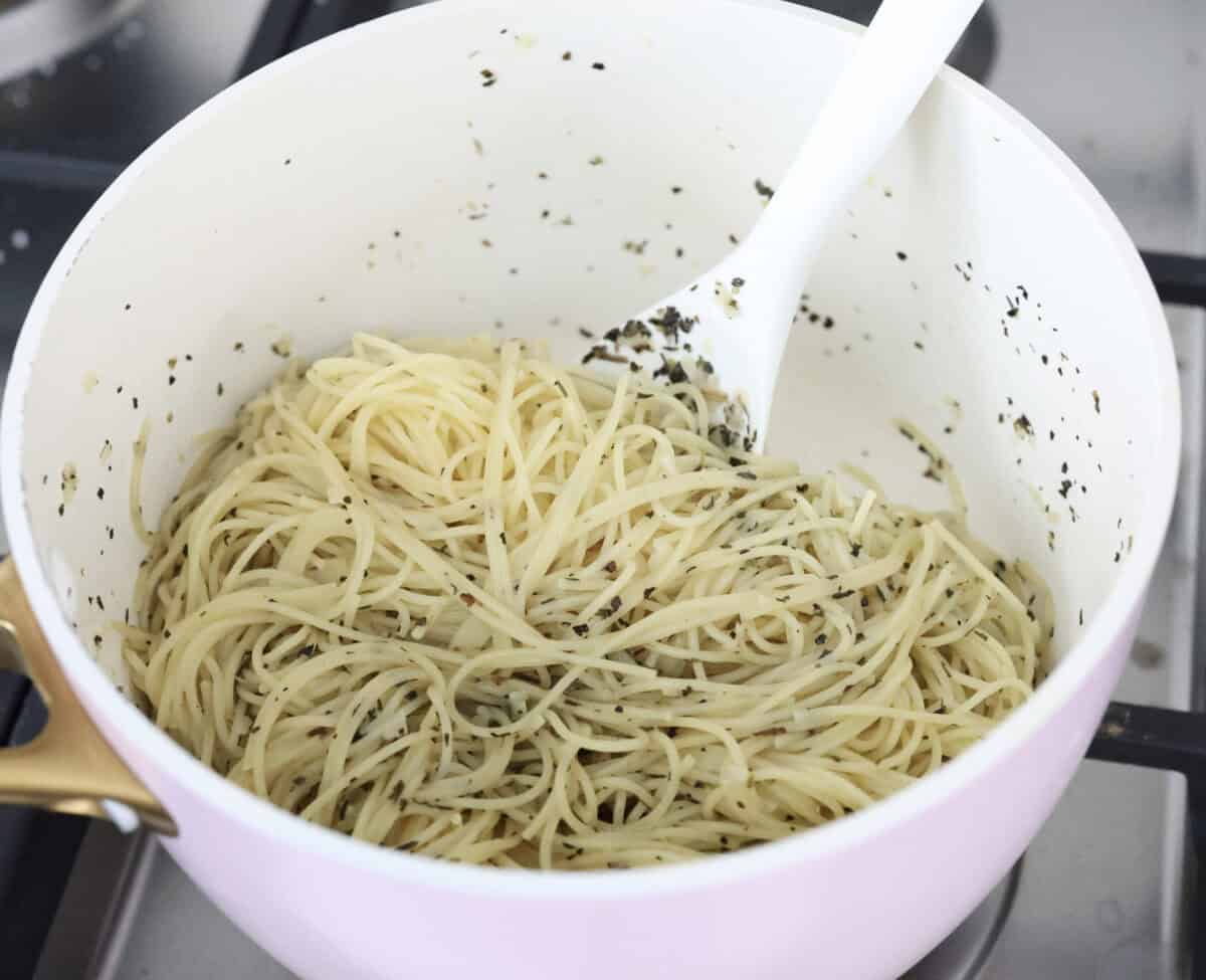 Garlic butter pasta is a quick and simple dish yet packed with flavor. Angel hair pasta is bathed in a buttery garlic sauce and topped with Italian seasoning. Angle shot of noodles mixed in with the butter garlic and seasoning.