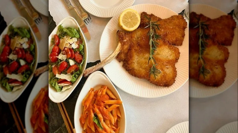 Cotoletto alla Milanese with a rosemary spring and half lemon on a plate with a small salad on the side