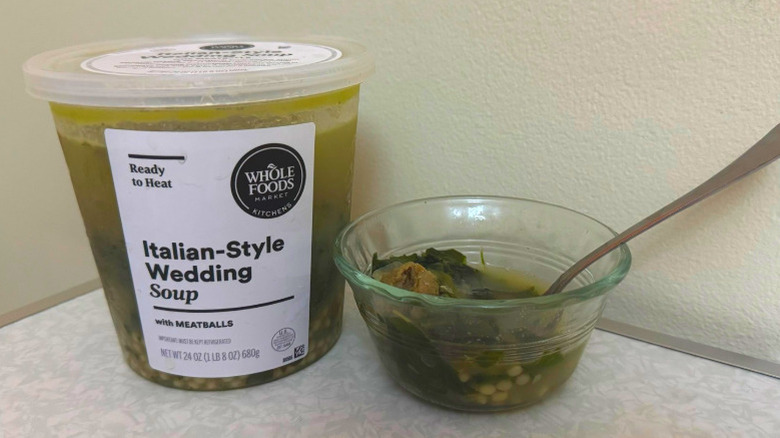 A tub and small glass bowl filled with Italian Wedding Soup