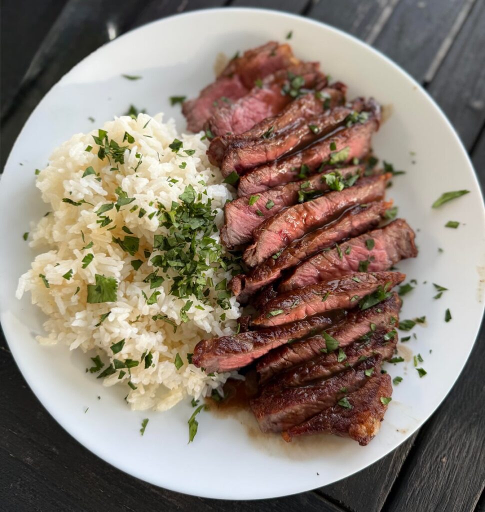New York strip with white rice and a red wine pan sauce drizzled over
