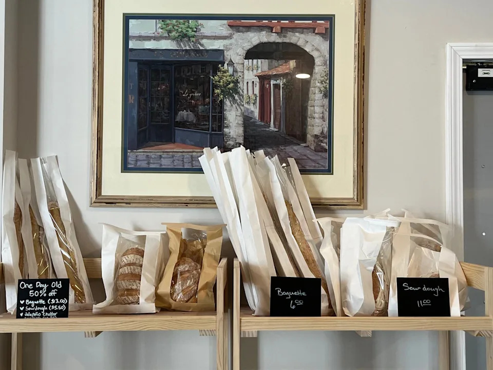 Le Cafe Gourmet's bread shelves hold both fresh sourdough baguettes and country loaves along with day-old baguettes marked down 50%.
