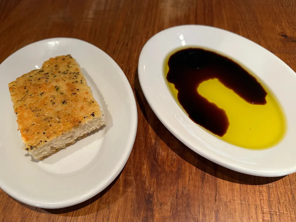 Chunk of bread on plate next to plate with olive oil, balsamic