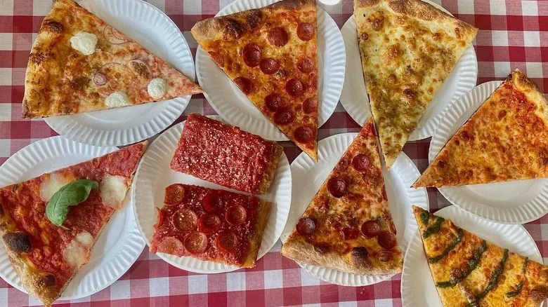 A variety of pizza slices on white paper plates and a red plaid tablecloth from Mano's Pizzeria