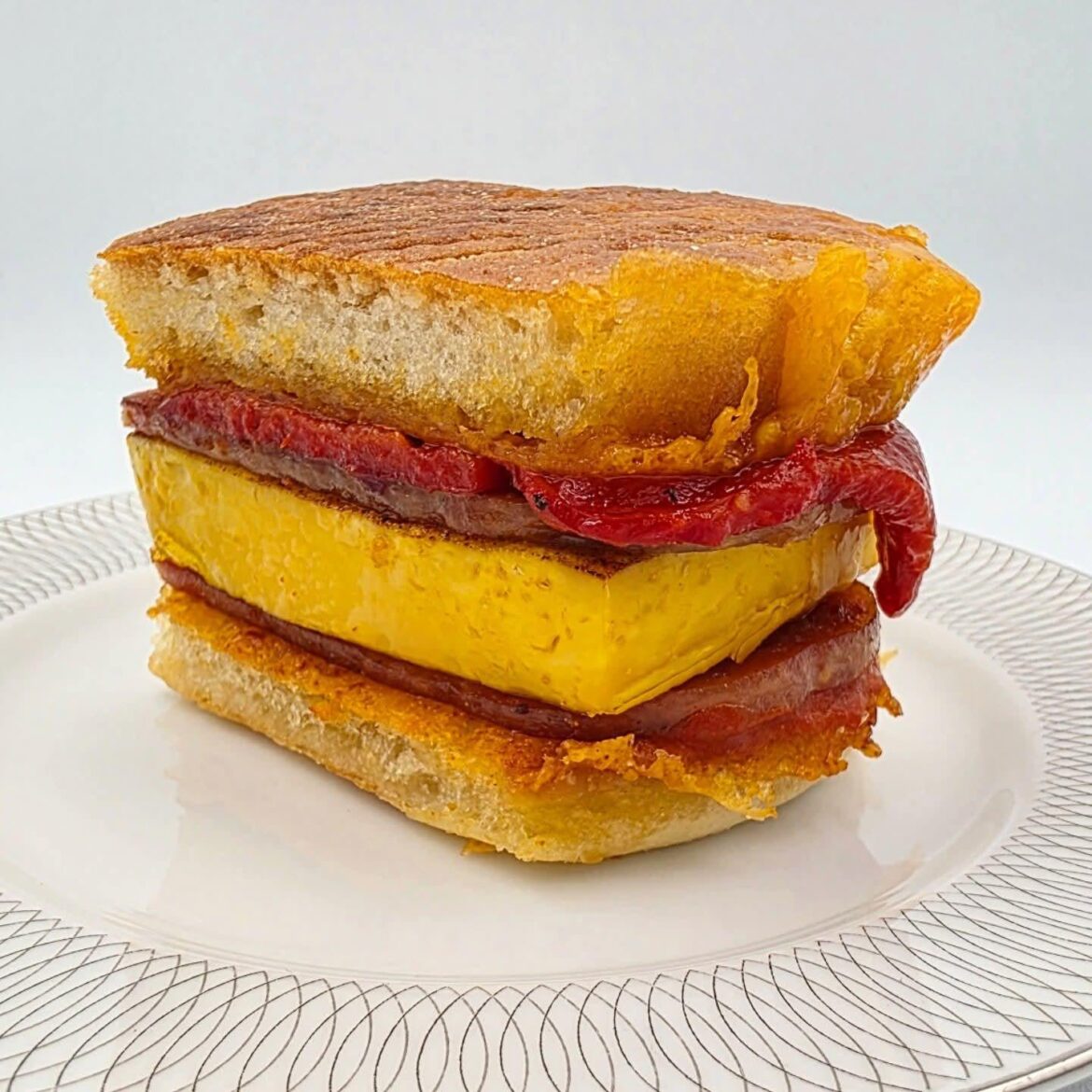 Sharp cheddar crusted buttermilk toaster biscuit, two slices of Original SPAM, fire roasted piquillo pepper, steamed dashi mushroom powder egg, Kewpie mayo, and Calabrian chili hot sauce