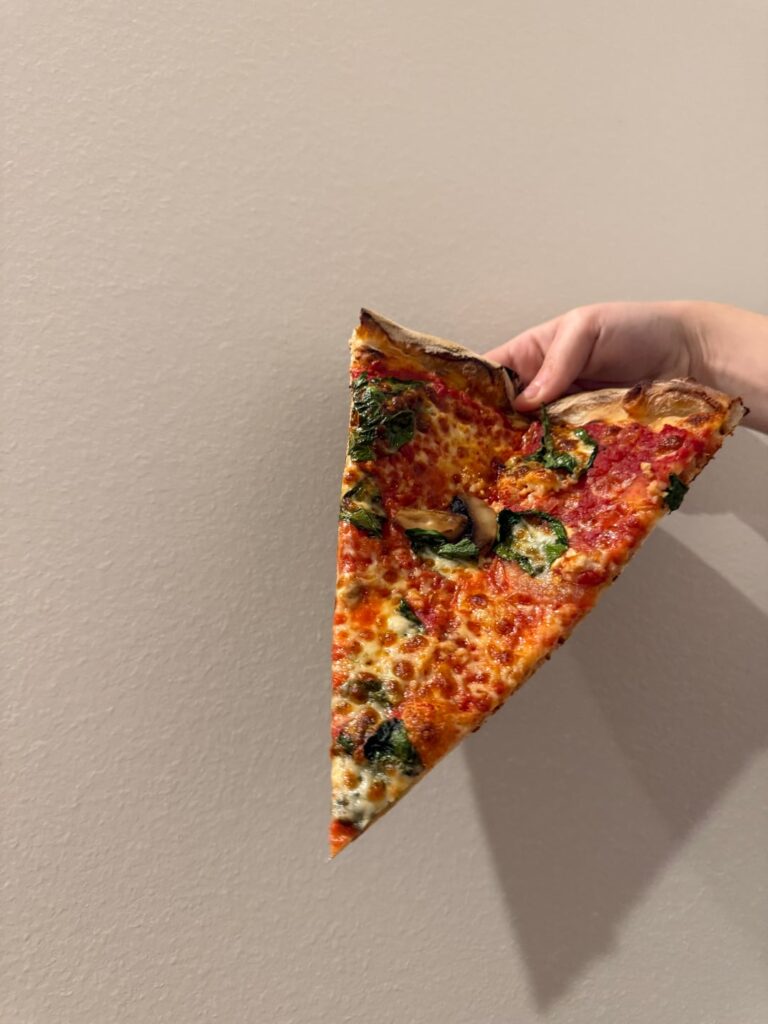 A slice from a 20” mushroom, tomato, spinach, and garlic pie.