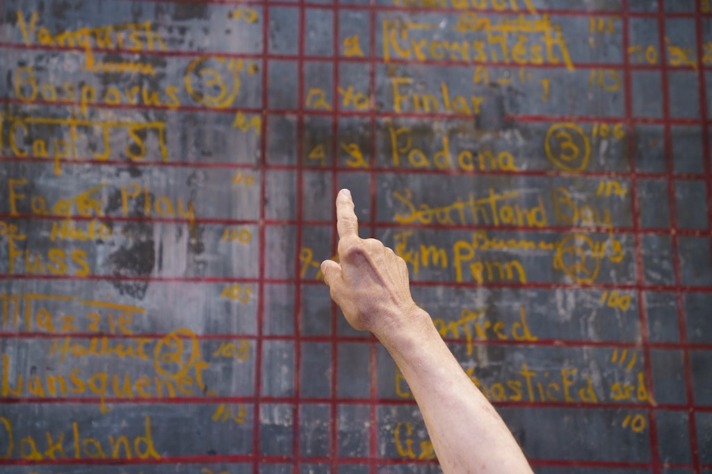 Bob Romiti, owner of Squire’s Italian Restaurant and Catering in Dundalk, Md., points out the jockeys’ weights listed on the blackboard. June 30, 2025.