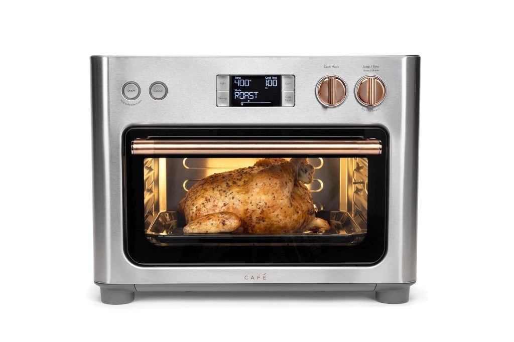 A stainless steel countertop oven with a chicken roasting inside. The display shows "Temp 400," "Cook Time 1:00," and "Mode ROAST."