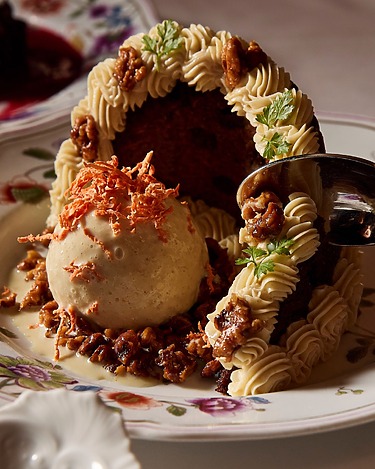 Dessert with ice cream, cake, and caramelized pecans on a floral plate.