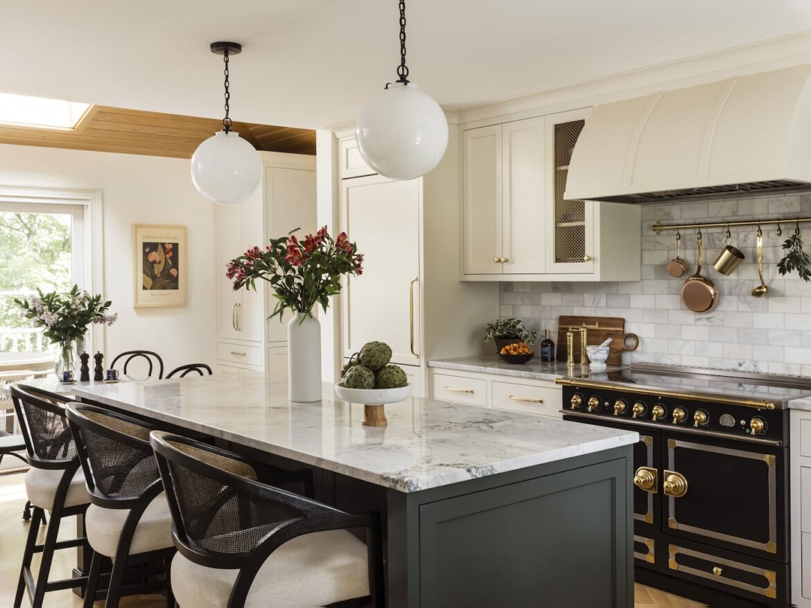 Kitchen with large center island with dark cabinets and white counter top. On the back wall there's a stove.