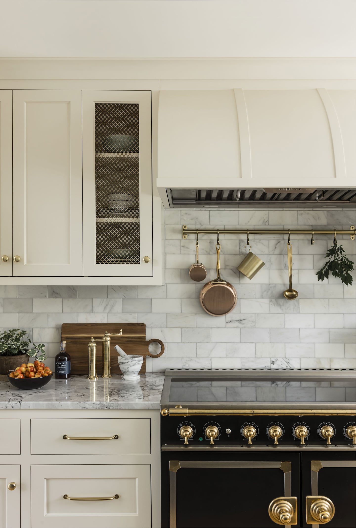 Wall in kitchen with the stove on the right, draws to the left, and white tile backsplash. There are white cabinets on the upper level.