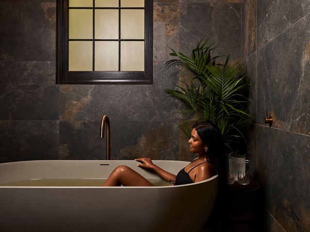 A woman bathes in the new Hepburn Bathhouse and Spa private bathing room with slate tiled walls