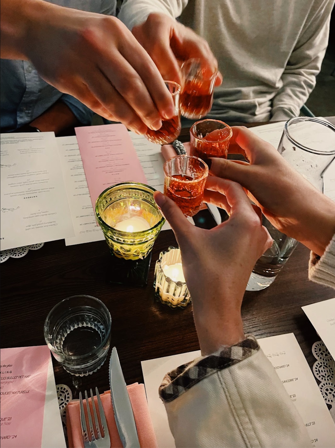 Guests at Bar Nouveau clink small glasses filled with welcoming sipping cocktails.