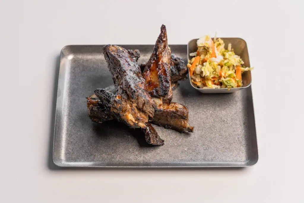 aerial view of lamb on a dark stone place with a small side salad set next to it. 