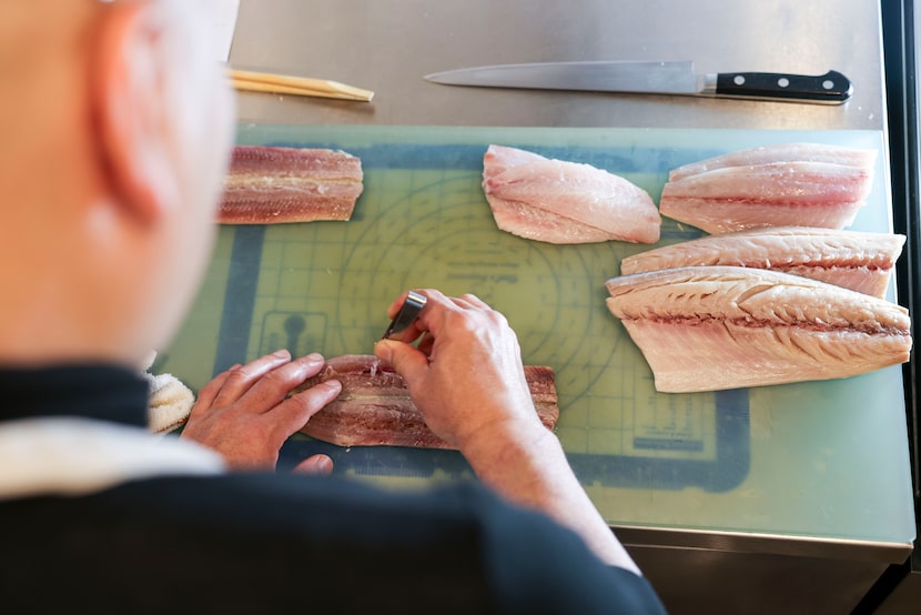 Chef Tatsuya Sekiguchi separates the bones from the fish as he prepares for service at his...