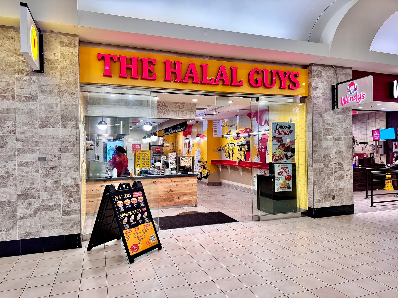 An image of a food stall inside a train station. A sign says The Halal Guys.