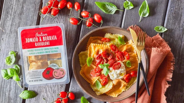 Trader Joe's tomato & burrata ravioloni in the package and prepared in a bowl and topped with tomatoes and cheese