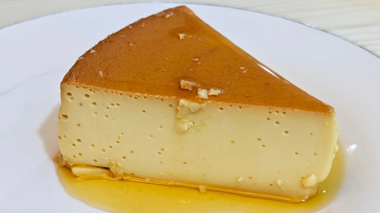 Triangular slice of creme caramel on a white plate