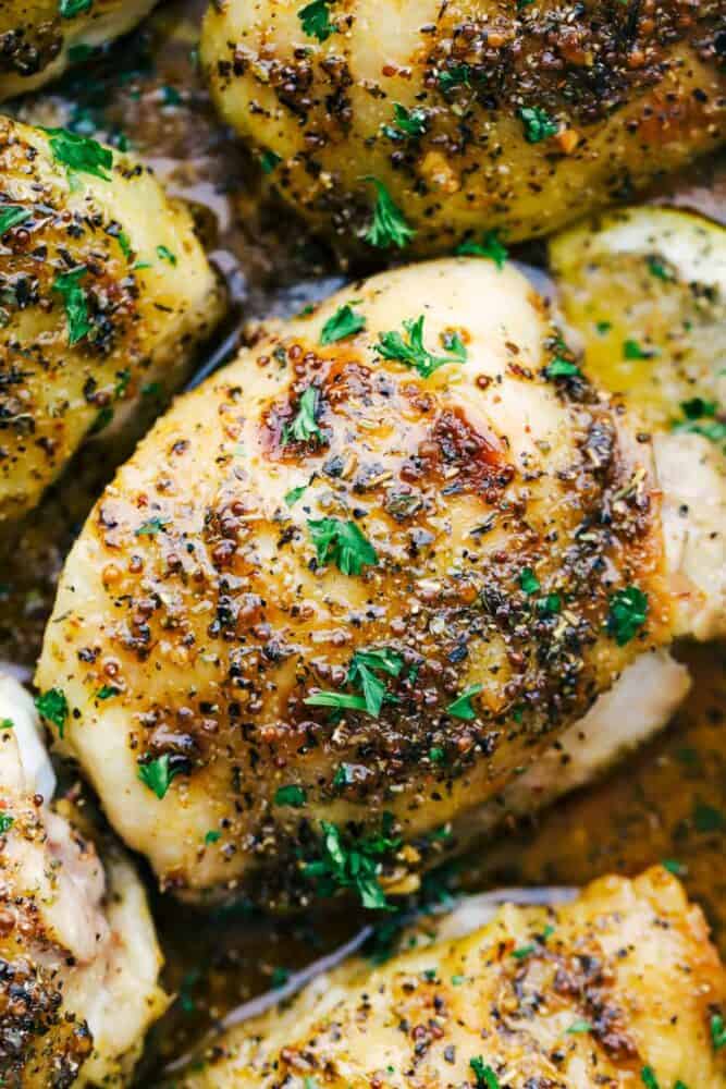 Baked Chicken Thighs are tender and juicy and baked in an AMAZING glaze mixture of Italian seasoning, Dijon mustard, sweet honey, and garlic cloves. This is a MUST make family meal! Baked chicken thighs close up.