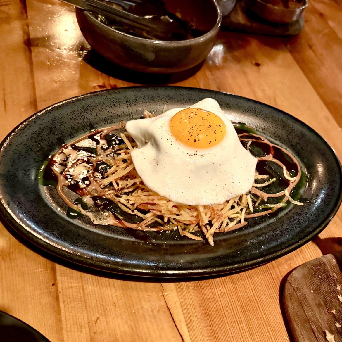 Roasted pig face over potato stix with tamarind, cilantro, red wine-maple gastrique, topped with an egg - YUM