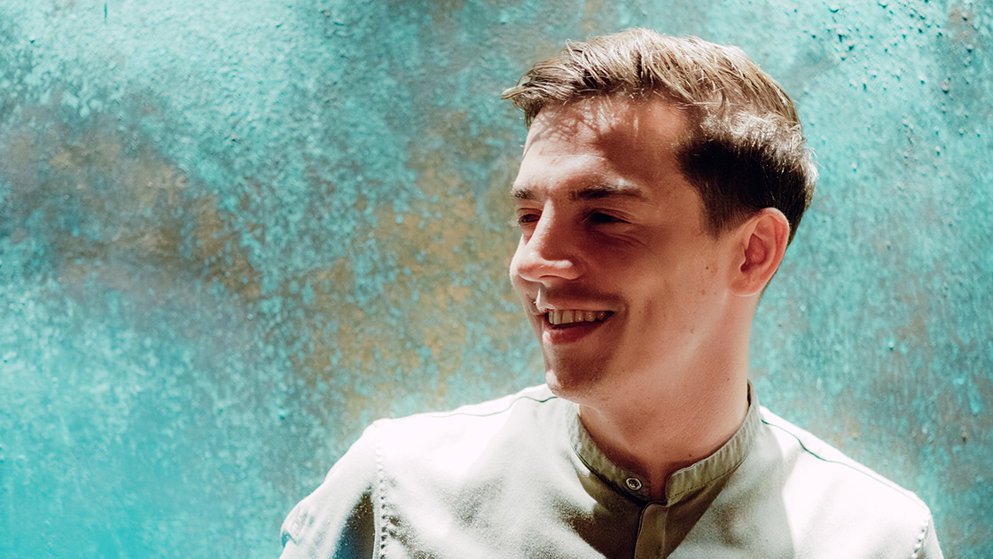 Mallory Gabsi with a turquoise wall as the backdrop, a nod to his mother, as it's her favorite color. © Mary Quincy / The MICHELIN Guide