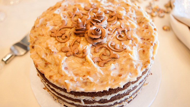Multi-layer German chocolate cake on tan table