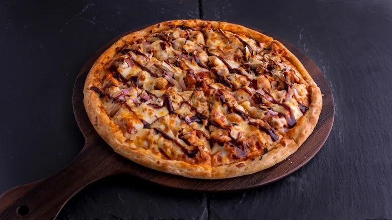 BBQ CHICKEN pizza isolated on cutting board top view on dark background Italian fast food