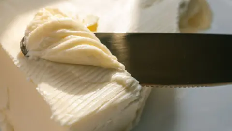 Getty Images Stock photo shows a close up image of a knife running through margarine with a spot of sunlight pouring in.