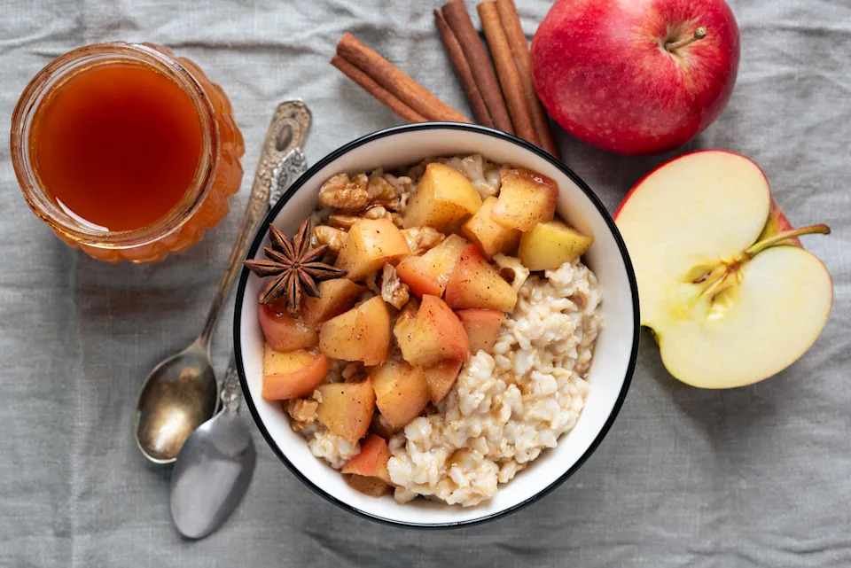 Oatmeal porridge with spiced apples and walnuts served in a bowl, top view. Autumn comfort food