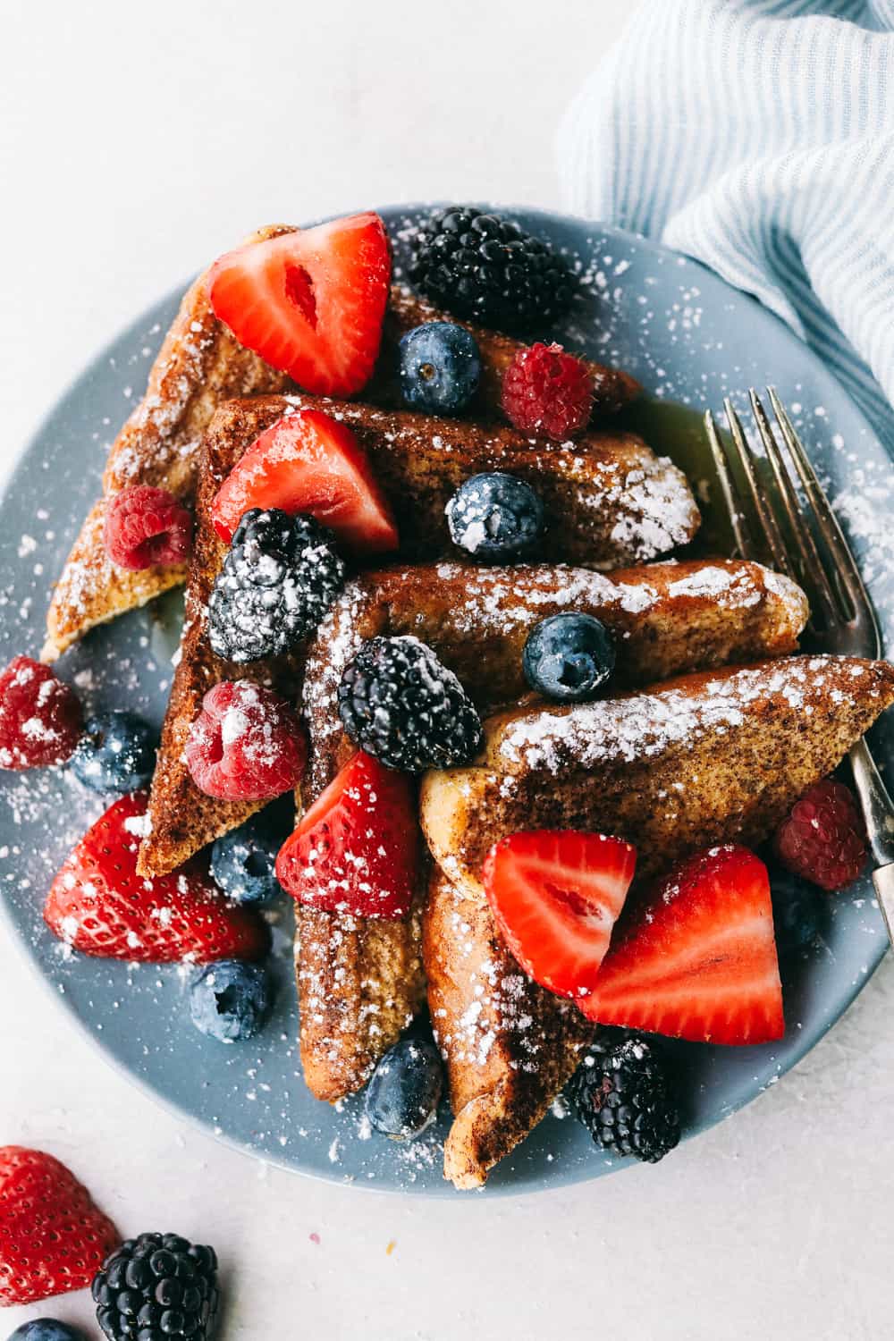 French Toast is a sliced thick, chunky bread dipped in a creamy egg, milk and cinnamon mixture with a secret ingredient that will take this French toast over the top! A little slice of heaven on your plate! sliced French toast with berries on a plate
