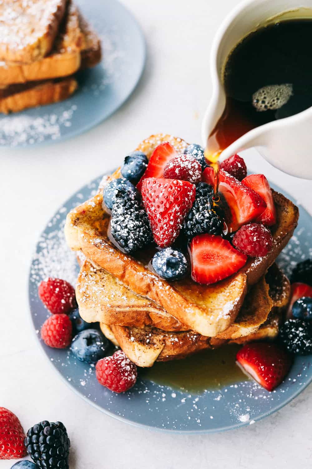 French Toast is a sliced thick, chunky bread dipped in a creamy egg, milk and cinnamon mixture with a secret ingredient that will take this French toast over the top! A little slice of heaven on your plate! French toast covered with berries, sprinkled with powdered sugar and syrup.