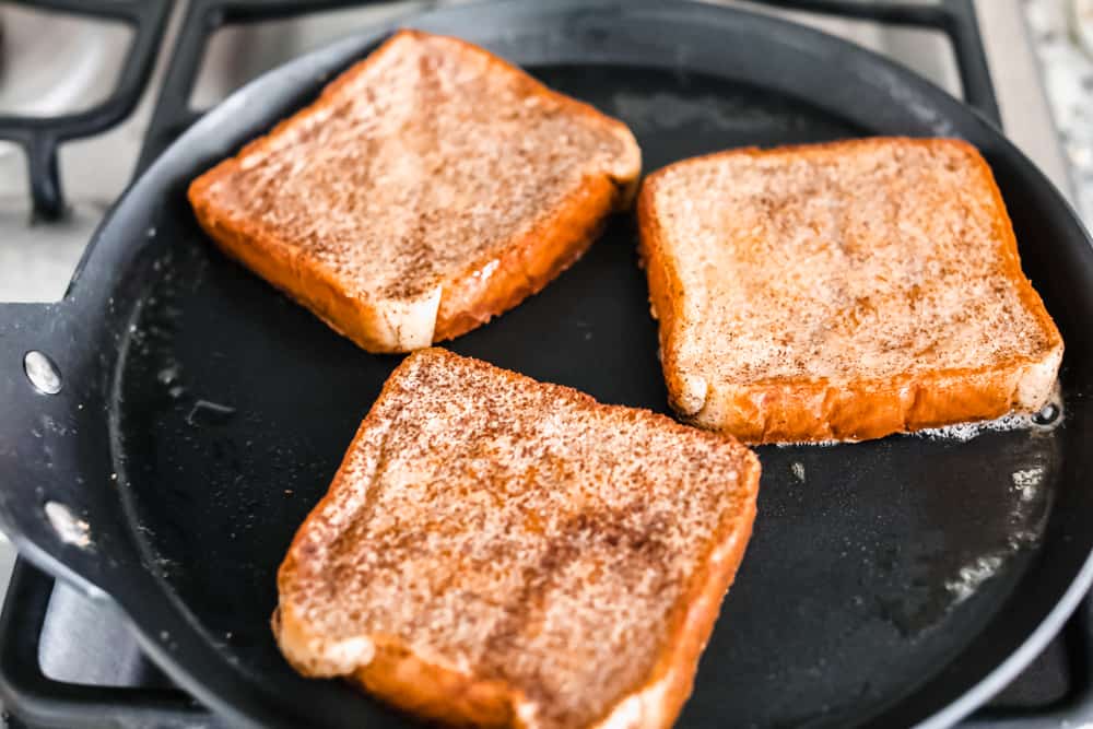 French Toast is a sliced thick, chunky bread dipped in a creamy egg, milk and cinnamon mixture with a secret ingredient that will take this French toast over the top! A little slice of heaven on your plate! cooking French toast in a skillet on the stove top.