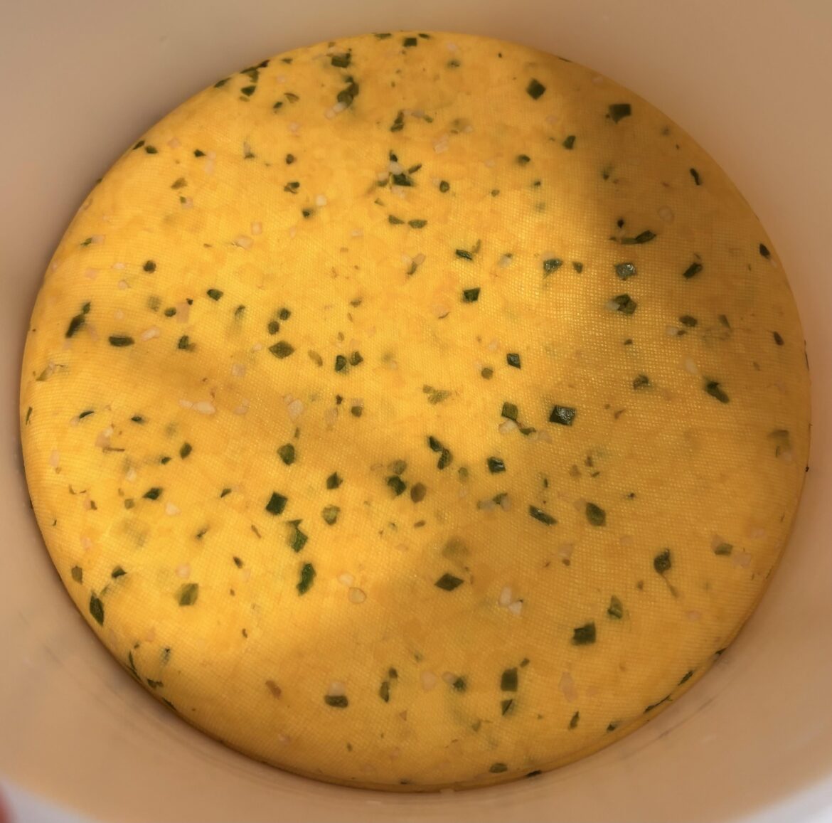 Sneak peek of a fresh wheel of homemade garlic Jalapeño Gouda cheese still in the press.