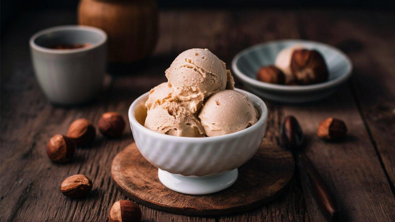 Hazelnut gelato served in a white bowl, with hazelnuts surrounding it