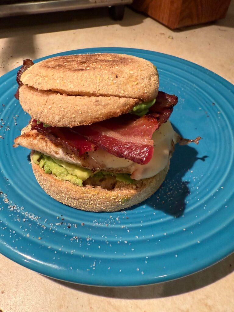 Avocado, egg, cheese, bacon on English muffin