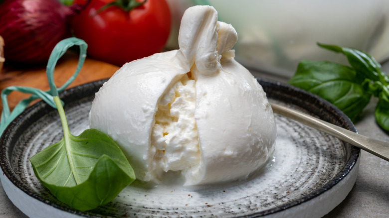 fresh burrata on a plate with a basil leaf