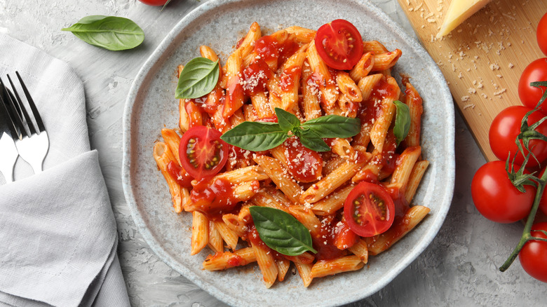 A plate of pasta with tomato sauce, basil, and fresh tomatoes