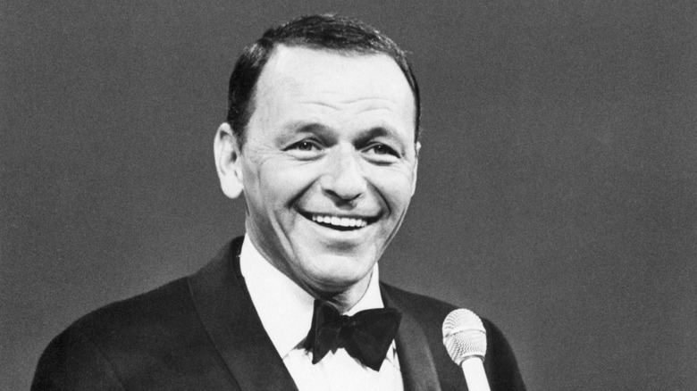 Close up of Frank Sinatra in a tux holding a microphone.