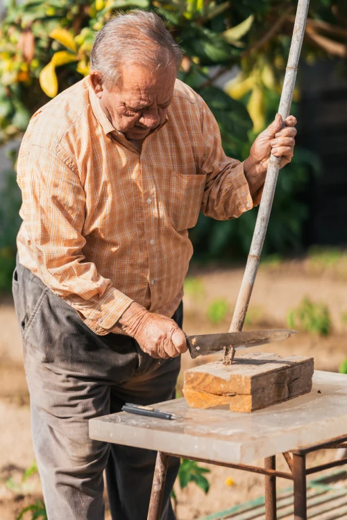 Elderly Italian man working on a craft project outdoors, an example of how keeping the mind active contributes to longevity | Photo: Depositphotos