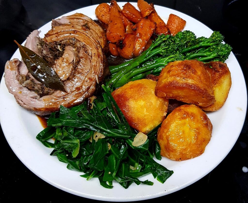 Monday Roast - Stuffed and Rolled Lamb Breast, Duck Fat Roast Potatoes, Glazed Carrots, Tenderstem Broccoli and Sauteed Garlic Cabbage. Red Wine Cranberry Gravy.